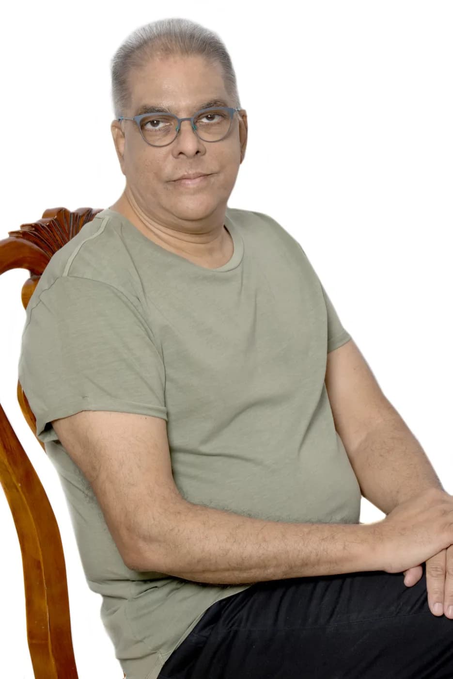 Dr RJ Sing in a studio portrait, seated in an olive T-shirt