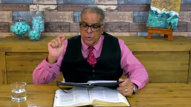 Dr RJ Sing teaching from his desk with an open Bible, Christmas Day 2020