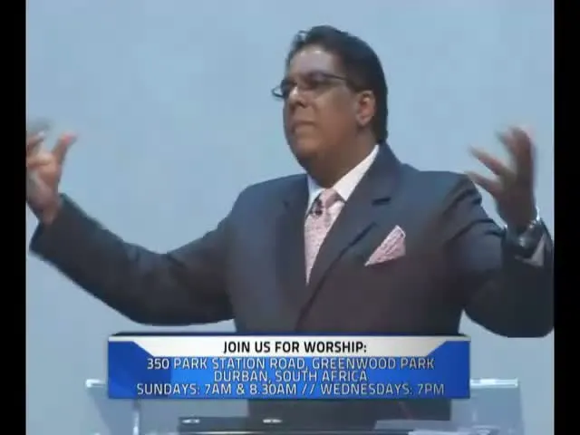Dr RJ Sing preaching with both arms raised, with the church's address at 350 Park Station Road on screen