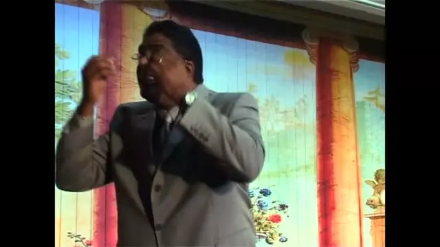 Dr RJ Sing preaching with passion, one hand raised