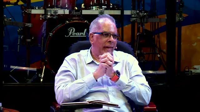 Dr RJ Sing smiling at the pulpit with his arms open wide, after the handover